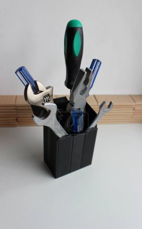 Photo for Variety Home Tools With Colored Handles Stacked In Plastic Box On White Shelf At Workshop - Royalty Free Image