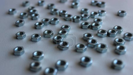 Closeup Image Of A Group Of Nuts Of The Same Diameter On White Surface Angle View. Hardware Background Stock Photo