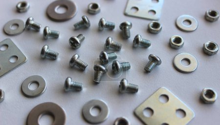 Macro photo of scattered washers, spacers, nuts and bolts on the white plastic sheet. Stock Photo For Fastener Hardware Backgrounds