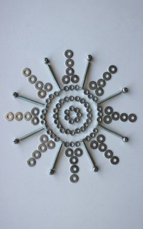 Arte del metal diseño vertical foto de stock. Flor hecha con pernos, tuercas y arandelas en superficie blanca