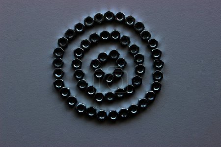 Patrón de círculos triples arreglado con tuercas de acero en blanco en la oscuridad 