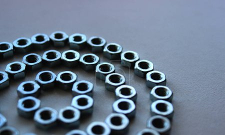 Tuercas de sujeción de acero colocadas en forma de tres círculos en la vista de ángulo de primer plano de superficie blanca 