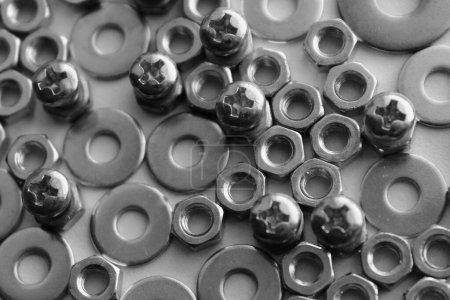 Cross head bolts inserted in hex nuts between scattered washers. Detailed stock photo for screw and fastener products illustration 