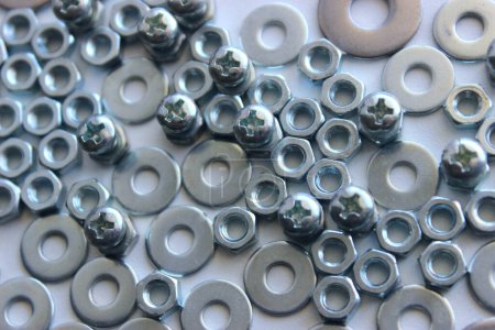 Steel color cross head bolts inserted in hex nuts between flat washers. Detailed stock photo for screw and fastener products illustration 
