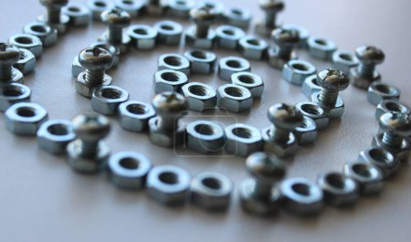 Photo for Concentrically arranged iron color nuts with bolts inserted into them reminiscent of part of a mechanism - Royalty Free Image