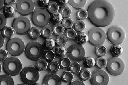 Fasteners And Screw Products Scattered On White Surface Black And White Stock Photo. Nuts And Bolts Hardware Royalty Free Background
