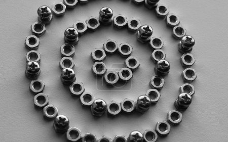 Flat Layer Of Cross Head Bolts, Fixing Nuts And Washers Scattered On White Surface. Grayscale Stock Photo For Hardware Backgrounds