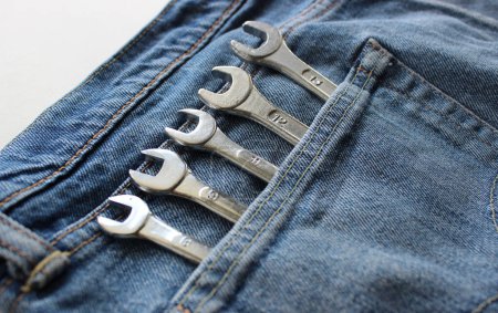 Closeup Angle View Of Heads Of Variety Diameter Shiny Hex Spanners Are Placed In Jeans Fabric Pocket. Household Tools And Home Renovation Concept Stock Photo 