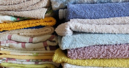 Washed home towels of different colors and materials are folded in two piles