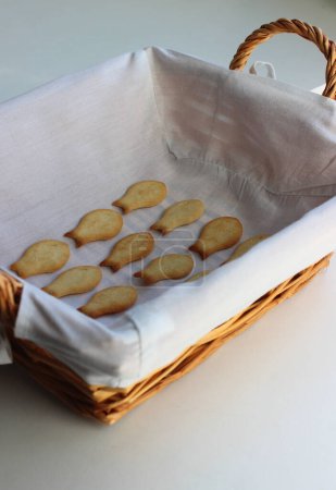 Ein mit einer weißen Serviette ausgekleidetes Strohbrotblech und frisch gebackene Cracker in Fischform. Hausgemachtes Backen vertikal Archivfoto
