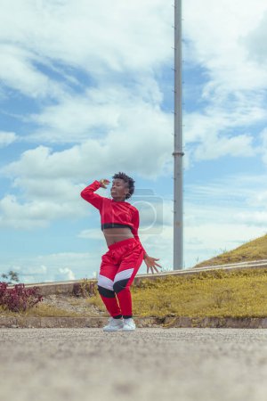 Photo for Jover mujer afro realiza baile estilo urban en parque local con hermoso y grande cielo y vegetacion. - Royalty Free Image