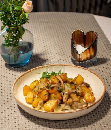 fried potatoes with rosemary in white plate on a wooden table with a napkin
