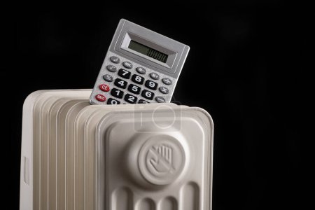 Téléchargez les photos : Graphique conceptuel sur les prix du chauffage avec calculatrice et radiateur électrique sur fond noir - en image libre de droit