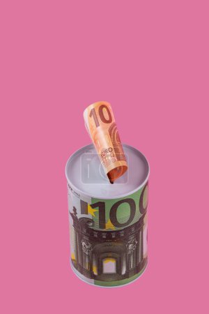 Foto de Hucha con la imagen de 100 euros y un billete de 10 euros sobre fondo rosa - Imagen libre de derechos