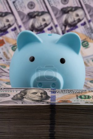 Foto de Blue piggy bank and a large stack of 100 American dollars bills - Imagen libre de derechos