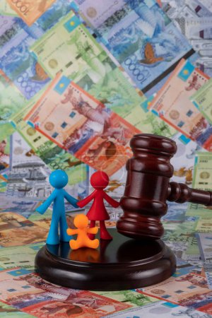 Judge's gavel and a symbolic family against the background of Kazakh banknotes - tenge