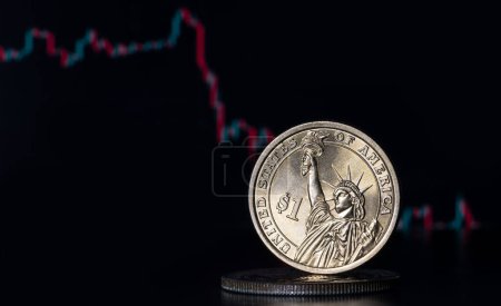 Téléchargez les photos : A coin in denomination of 1 American dollar stands on a computer keyboard against the background of a stock summary chart - en image libre de droit