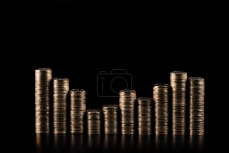Coins in denominations of 100 Kazakhstani tenge stacked in several columns on a black background