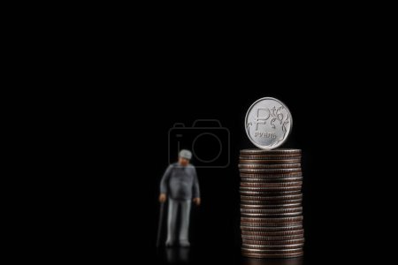 Téléchargez les photos : Complot conceptuel sur l'épargne-pension en Russie avec une figurine d'un retraité et une pièce de monnaie avec le symbole du rouble russe - en image libre de droit