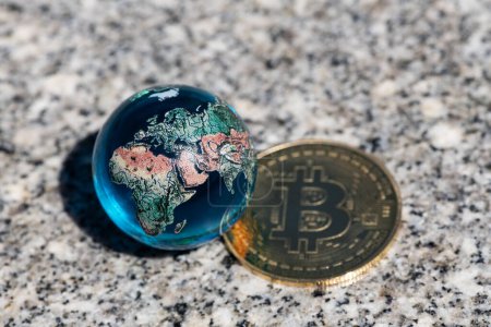 Téléchargez les photos : Pièce d'or avec Bitcoin symbole crypto-monnaie et globe en verre symbolique - en image libre de droit