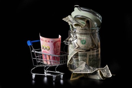 100 chinesische Yuan-Schein im Warenkorb und Glas mit 1 US-Dollar-Scheinen
