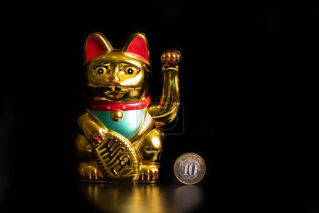 Symbolische Figur einer chinesischen Souvenir-Katze, die finanzielles Glück und eine Münze in Höhe von 10 chinesischen Yuan bringt