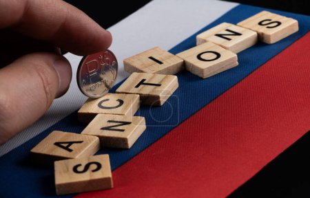 Coin with the symbol of the Russian ruble, the flag of Russia and the words "sanctions"