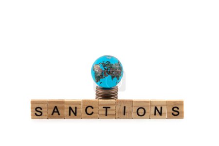 Glaskugel, Münzen und das Wort "Sanktionen" auf weißem Hintergrund