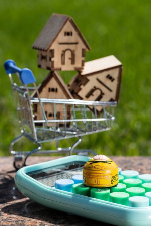 Miniatur-Jurte, Taschenrechner und symbolische Häuser im Einkaufswagen des Supermarktes
