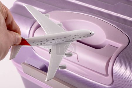 Avion passager symbolique en main sur fond de valise de voyage