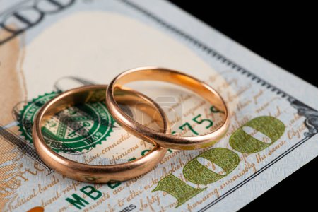 Anneaux de mariage en or sur le fond d'un fragment d'un billet de 100 dollars