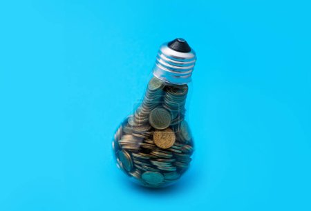 Konzeptgeschichte über die Stromkosten in Kasachstan mit einer Glühbirne, die mit Münzen im Wert von 1 kasachischen Tenge gefüllt ist