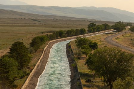 Large artificial irrigation canal filled with water on a sunny day