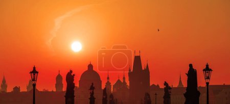 Sonnenaufgang über der Hauptstadt der Tschechischen Republik - Prag mit Silhouetten von Gebäuden und Statuen