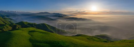 View from a quadcopter of a picturesque hilly mountain landscape with fog at sunset on a spring day