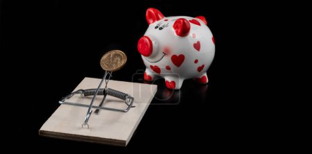 Mousetrap, 1 US dollar coin and piggy bank on a black background