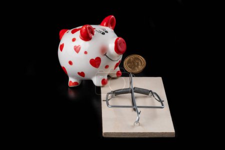 Mousetrap, 1 US dollar coin and piggy bank on a black background