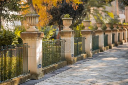 Téléchargez les photos : Jardins universitaires à La Valette, Malte par une journée ensoleillée. Vue d'une rangée de piliers avec clôture. - en image libre de droit