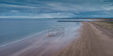 Foto de Avión no tripulado pintoresco panorama de la playa de arena en Castlerock, Irlanda del Norte en el día nublado de primavera. Nubes oscuras, viento y marea baja en Castlerock ciudad costera. - Imagen libre de derechos