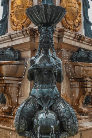 Foto de Detalle de la estatua en el parque central o plaza en el centro de Batumi, Georgia. Fuente de agua rodeada de diferentes edificios de colores y palmeras. Día soleado, sirena lactante. - Imagen libre de derechos
