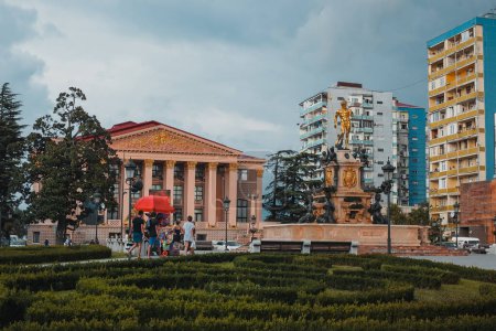Foto de Parque central o plaza en el centro de Batumi, Georgia. Fuente de agua rodeada de diferentes edificios de colores y palmeras. Día soleado - Imagen libre de derechos