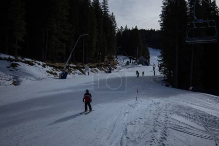 Photo for Skiing on rogla middle track. Ski slope of rogla, with visible cable ropeway in the background, some skiers on the slopes. Cold winter day with some sun. View from the cable car. - Royalty Free Image