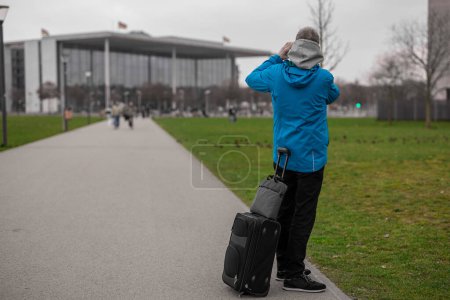 Foto de Hombre desconocido o viajero fotografiando una casa de fachada de vidrio en negocios o parte gubernamental de Berlín en un día nublado - Imagen libre de derechos