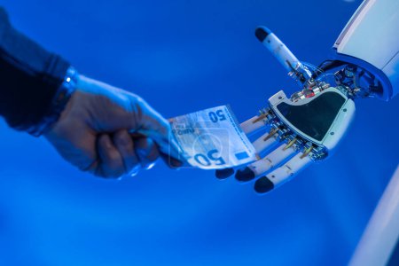 Hand einer Person, die einem Roboterarm 50 Euro gibt. Roboter erhalten Geld von einer Person. Konzept von Robotern und künstlicher Intelligenz, die Arbeitskräfte und Menschen übernehmen. Blauer Rahmen