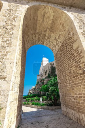 Arch bridge at Polignano a Mare, beautiful city with a beach between the city cliffs. Colorful picture of a picturesque village in italian puglia on a sunny spring day.