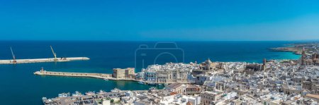 Weites Drohnenpanorama der Stadt Monopoli an der italienischen Küste in der Region Apulien an einem sonnigen Frühlingstag. Sichtbarer Hafen und alte Häuser
