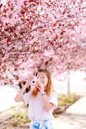 Photo for Beautiful woman with blooming Sakura tree and sunny day - Royalty Free Image