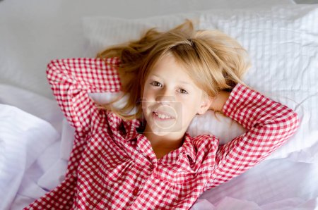 Foto de Image of young smiling pretty girl lies in bed indoors. - Imagen libre de derechos