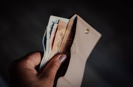 Foto de Mujer sacando dinero en euros de su cartera de bolsillo. Hombre contando dinero, concepto de economía, distribución de dinero - Imagen libre de derechos