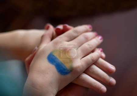 female hands painted in Ukraine flag colors yellow-blue. Stop the war and the power of Ukraine, patriotism and Kiev, strength and power